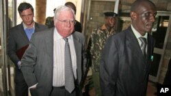 FILE - Jerome Corsi, center, who wrote "The Obama Nation: Leftist Politics and the Cult of Personality, follows an immigration department officer holding his passport.