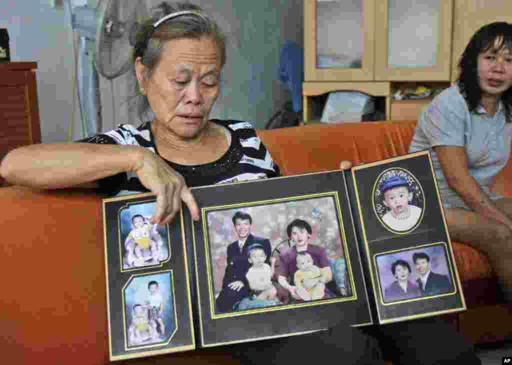 Suwarni, whose son was onboard flight MH370 with his wife, shows her son's family portraits at her residence in Medan, North Sumatra, Indonesia, March 25, 2014. 