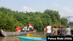 Aktivis lingkungan menyerukan kemerdekaan bagi lingkungan dan menggelar upacara bendera di muara sungai Wonorejo, ekosistem hutan mangrove dalam peringatan HUT Kemerdekaan Indonesia ke-71. (Foto: VOA/Petrus Riski).