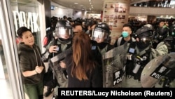 Cảnh sát chống bạo động đối đầu một người biểu tình mặc đồ đen trong trung tâm mua sắm Harbour City ở Hong Kong, Trung Quốc, ngày 21 tháng 12, 2019.