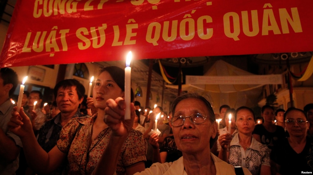 FILE - Protesters hold candles during a mass prayer for political dissident Le Quoc Quan at Thai Ha church in Hanoi June 30, 2013. 