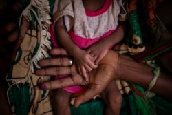 Abeba Gebru, 37, from the village of Getskimilesley, holds the hands of her malnourished daughter, Tigsti Mahderekal, 20 days old. (AP Photo/Ben Curtis)
