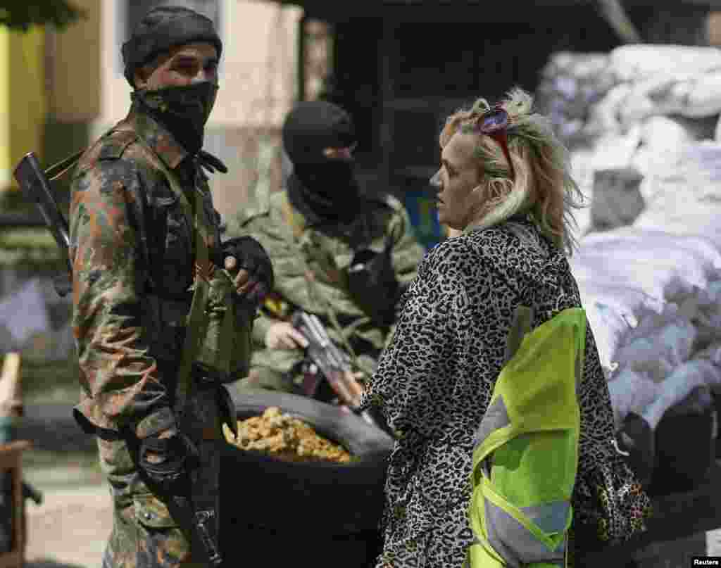Galina Kovalchuk, the mother of detained Vitaliy Kovalchuk, speaks with an armed pro-Russian man as he stands guard at a barricade near the captured state security service building in Slovyansk, April 28, 2014.
