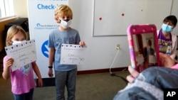 FILE - Leah Malloy, 6, and her brother Owen Malloy, 9, take photos with COVID-19 vaccine certificates after receiving the Pfizer vaccine for children 5 to 11 years as Lurie Children's hospital registered nurse Jeanne Bailey, right, looks on, Nov. 5, 2021, in Chicago.