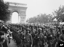 FILE-In this photo provided by the U.S. Office of War Information, American troops march down the Champs Elysees, past the Arc de Triomphe, Sept. 12, 1944, as residents of Paris throng the sidewalks to cheer.