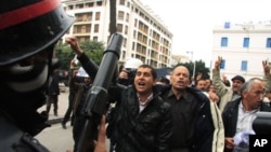 A riot policeman faces off with protesters during a demonstration in downtown Tunis, Tunisia, 18 Jan 2011