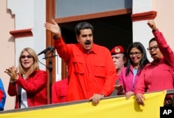 Venezuela's President Nicolas Maduro, center, and first lady Cilia Flores, left, interact with supporters from a balcony at Miraflores presidential palace during a rally in Caracas, Venezuela, Jan. 23, 2019.