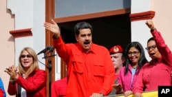 Venezuela's President Nicolas Maduro, center, and first lady Cilia Flores, left, interact with supporters from a balcony at Miraflores presidential palace during a rally in Caracas, Venezuela, Jan. 23, 2019. 