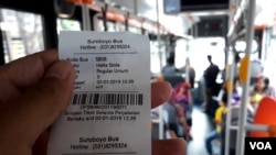 Tiket Suroboyo Bus diterima penumpang setelah menukar botol dan gelas plastik bekas kepada petugas di dalam bus (foto Petrus Riski/VOA).