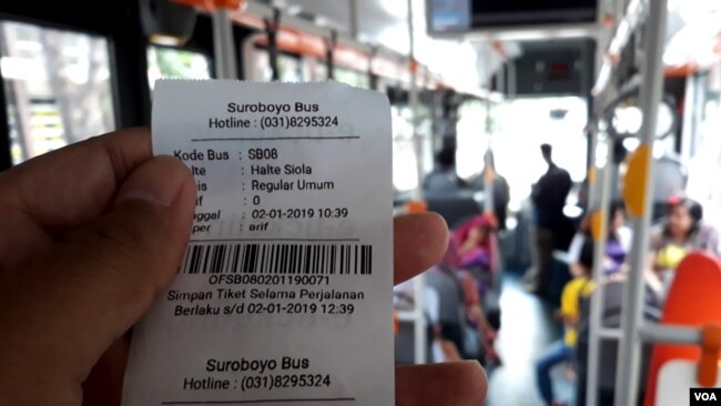 Tiket Suroboyo Bus diterima penumpang setelah menukar botol dan gelas plastik bekas kepada petugas di dalam bus (foto Petrus Riski/VOA).