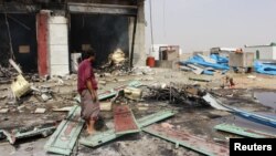 A man stands at the scene of an airstrike that hit a truck at a gas station in Abss, Yemen, April 24, 2018. 