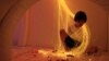 A boy relaxes with lights in a 'Snoezelen' room during yoga classes for children who typically have autism, brain injuries or developmental disabilities, in Lima, Peru, Jan. 27, 2012.