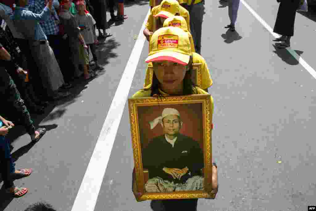 Girls walk holding a picture of General Aung San in Yangon as Myanmar observes the 72nd anniversary of Martyrs' Day, marking the assassination of independence heroes, including Aung San Suu Kyi's father, who helped end British colonial rule.