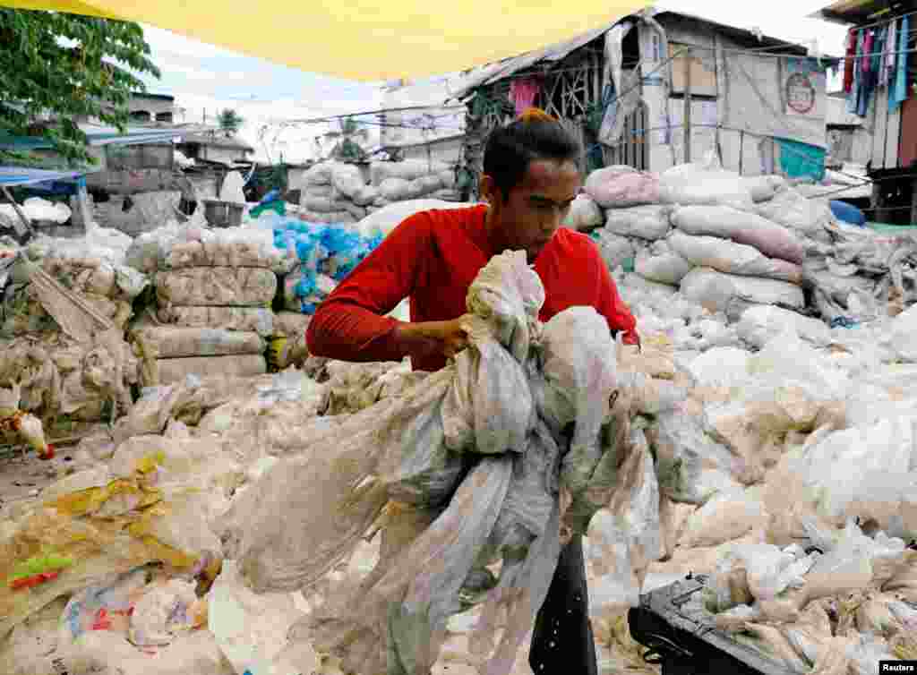 A man lifts plastic at a makeshift recyling facility at Payatas district, Quezon City, Manila, Philippines.