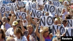 Civil servants hold up placards as they protest against government austerity measures in Madrid, July 23, 2012.