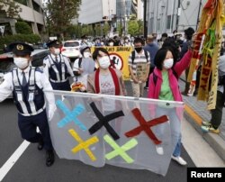 FILE - People protest the Tokyo 2020 Olympics amid the coronavirus outbreak, around Olympic Stadium (National Stadium) as an Olympic test event for athletics is held inside the venue in Tokyo, Japan, May 9, 2021, in this photo taken by Kyodo.