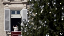 El papa Francisco saluda desde el balcón durante la oración del Angelus, con el árbol de Navidad del Vaticano en primer plano.