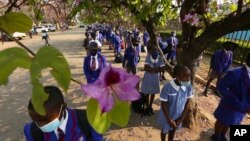 Schoolchildren wait to enter their school in Harare, Zimbabwe, Monday Sept, 28, 2020. Zimbabwe schools have reopened in phases, but with smaller number of pupils, more teachers and other related measures to enable children to resume their education withou