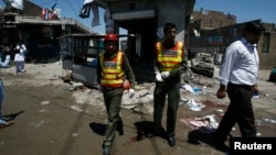 Rescue workers and journalists are seen outside the election campaign office of candidate Nasir Khan Afridi that was damaged in a bomb blast in Peshawar April 28 , 2013. 