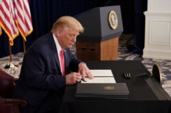El presidente Donald Trump firma órdenes ejecutivas sobre beneficios de ayuda por el coronavirus, en su club de golf en Bedminster, Nueva Jersey, el sábado 8 de agosto de 2020.