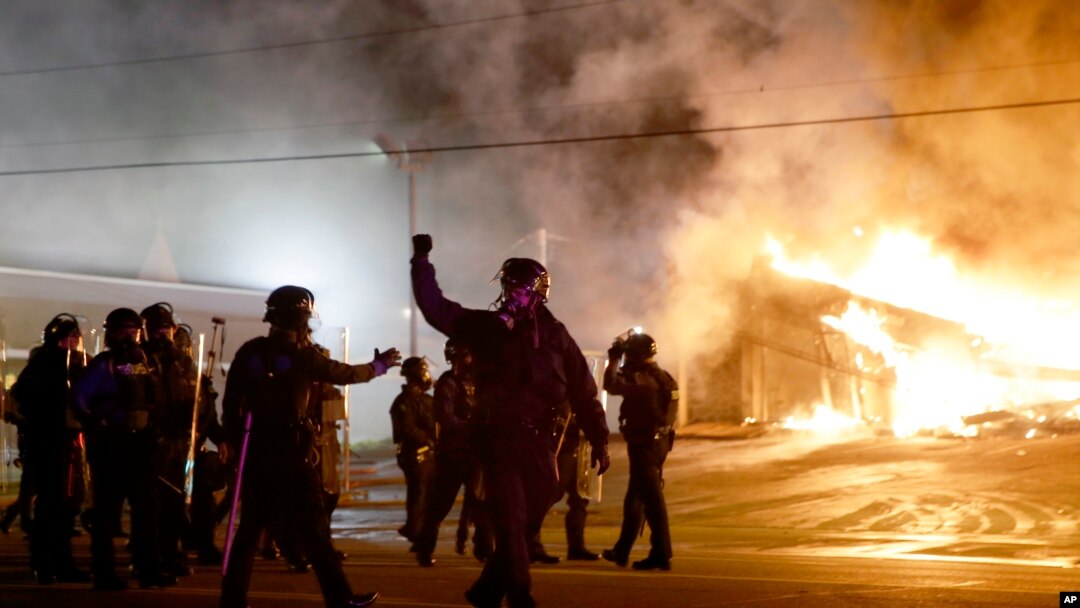 Polisi mengamankan kota Ferguson, Missouri sementara demonstran membakar sebuah gedung di sana, Senin (24/11).