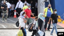 Refugees from Kara Tepe camp board a ferry in the port of Mytilene, Lesbos, September 28, 2020. About 700 refugees are being transferred to the mainland, three weeks after a fire destroyed the notorious Moria camp leaving more than 12,000 people homeless.