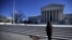 Flowers are seen as a woman stands in front of the Supreme Court building in Washington, D.C., after the death of U.S. Supreme Court Justice Antonin Scalia, Feb. 14, 2016.