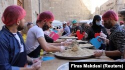 Relawan dari organisasi amal "Saed" menyiapkan makanan untuk dibagikan kepada orang-orang yang membutuhkan selama bulan suci Ramadhan, di Damaskus, Suriah, 23 April 2021. (Foto: REUTERS/Firas Makdesi)