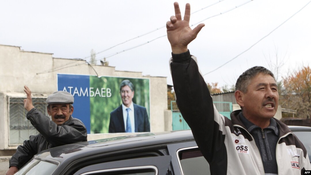 Local residents gesture, with a poster displaying Kyrgyzstan's Prime Minister and presidential candidate Almazbek Atambayev, in the village of Arashan outside the capital Bishkek October 26, 2011. Twenty candidates will vie for the presidency of Kyrgyzsta