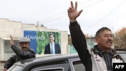 Local residents gesture, with a poster displaying Kyrgyzstan's Prime Minister and presidential candidate Almazbek Atambayev, in the village of Arashan outside the capital Bishkek October 26, 2011. Twenty candidates will vie for the presidency of Kyrgyzsta