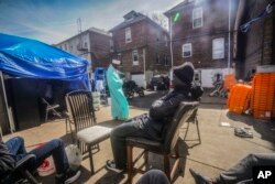 FILE—Senegalese migrant Malick Thiam, 29, center, relaxes, as Imam Omar Niass, top, walks in the backyard of Bronx's Masjid Ansaru-Deen mosque where migrants have installed tents, March 15, 2024, in New York.