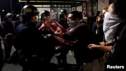  A masked demonstrator scuffles with police officers during a demonstration following the election of Donald Trump as president of the United States, in Oakland, California, Nov. 10, 2016.