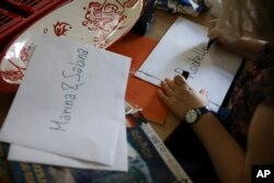 Marta Saracyn, the head of the Jewish Community Center of Warsaw, writes down names of the children at the Lauder Morasha Jewish school in Warsaw, Poland, Thursday, July 28, 2022. (AP Photo/Michal Dyjuk)