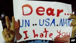 In this citizen journalism image made and provided by the Kfar Suseh Coordinating of the Syrian Revolution on June 18, 2012, anti-Syrian regime protesters hold up a placard during a demonstration at Kfar Suseh area, in Damascus, Syria.