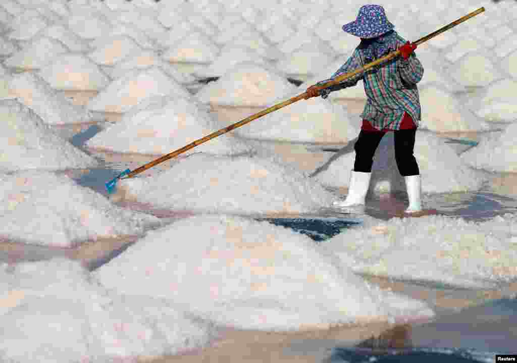 A woman works on a salt farm in Phetchaburi, Thailand, May 9, 2020.