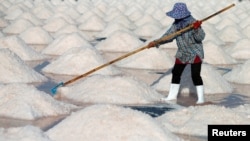 FILE - A woman works on a salt farm in Phetchaburi, Thailand, May 9, 2020. The three main economic industries driving Thailand's gross domestic product are manufacturing, agriculture and services. 