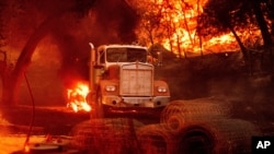 FILE - Flames from the Glass Fire burn a truck in a Calistoga, Calif., vineyard Oct. 1, 2020.