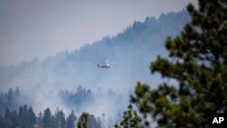 A helicopter pilot prepares to drop water on a wildfire burning in Lytton, British Columbia, July 2, 2021. Officials on Friday hunted for any missing residents of the town, which was destroyed by wildfire.