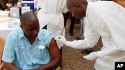 FILE - A health worker prepares to inject a man with an Ebola vaccine in Conakry, Guinea, March 7, 2015.