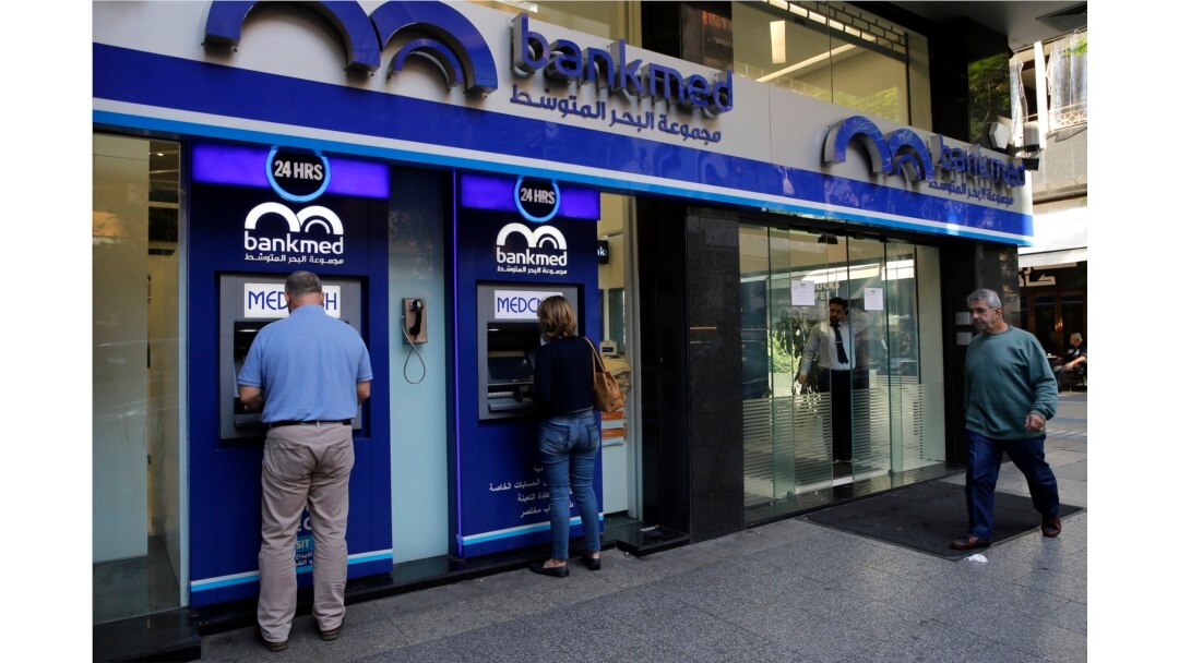 FILE - People use an ATM outside a bank, in Beirut, Lebanon, Nov. 20, 2019.