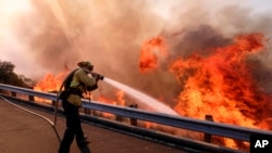 A firefighter battles a fire along the Ronald Reagan (118) Freeway in Simi Valley, California, Nov. 12, 2018.