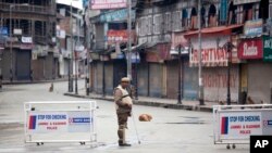 An Indian policeman stands guard at a temporary checkpoint during a curfew in Srinagar, India, March 14, 2013.