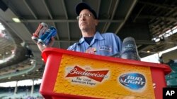 FILE - A beer vender holds up Budweiser and Bud Light at Wrigley Field in Chicago, Oct. 13, 2015.