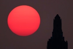 The Power and Light Building is silhouetted against the hazy rising sun, Sept. 18, 2020, in Kansas City, Mo. Sunrises and sunsets across much of the country have been more vibrant than usual as smoke from Western wildfires drifts across the nation.