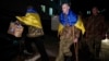 Ukrainian serviceman Yevhen Liashenko uses crutches as he arrives to be reunited with his wife after returning from Russian captivity, during a prisoner of war exchange at an unidentified location in Ukraine, Dec. 30, 2024.