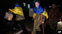 Ukrainian serviceman Yevhen Liashenko uses crutches as he arrives to be reunited with his wife after returning from Russian captivity, during a prisoner of war exchange at an unidentified location in Ukraine, Dec. 30, 2024.