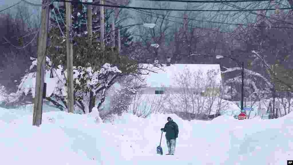 Un homme prend a pris un congé pour enlever la neige devant chez lui dans la zone sud de Buffalo jeudi 20 novembre 2014, à Buffalo, NY. Une nouvelle tempête de neige s&rsquo;est abattue sur Buffalo pour la troisième journée consécutive causant plus de misère à une ville déjà enterrée par une tombée de neige meurtrière qui pourrait laisser quelques zones avec près de 2,5 mètres de neige.