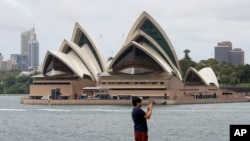 FILE - A man films the harbor foreshore on his mobile phone ahead of New Years Eve in Sydney, Australia, Dec. 31, 2020. 