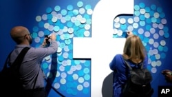 FILE - People stick notes on a Facebook logo at a Facebook developer conference, in San Jose, California, April 30, 2019. 