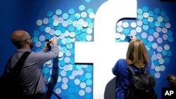 FILE - People stick notes on a Facebook logo at a Facebook developer conference, in San Jose, California, April 30, 2019.